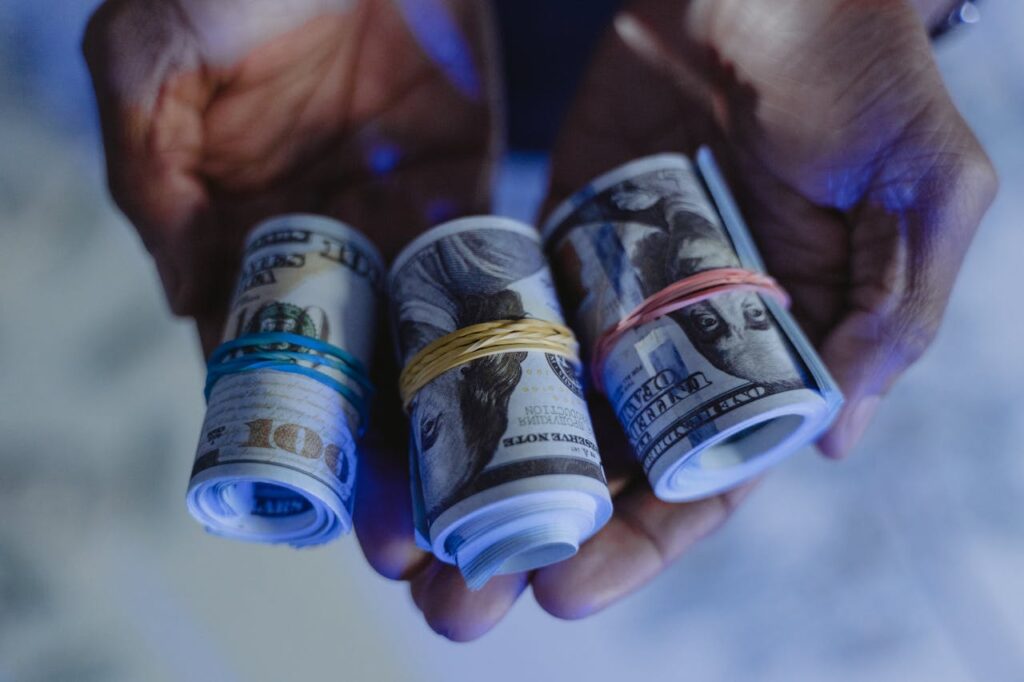 A Person Holding a Sum of Rolled Cash